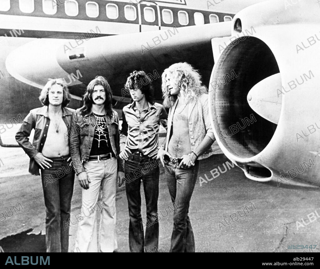 Led Zeppelin stands beneath wing of their plane Starhip One. (1-r) John Paul Jones, John Bonham, Jimmy Page, Robert Plant. July 1973.