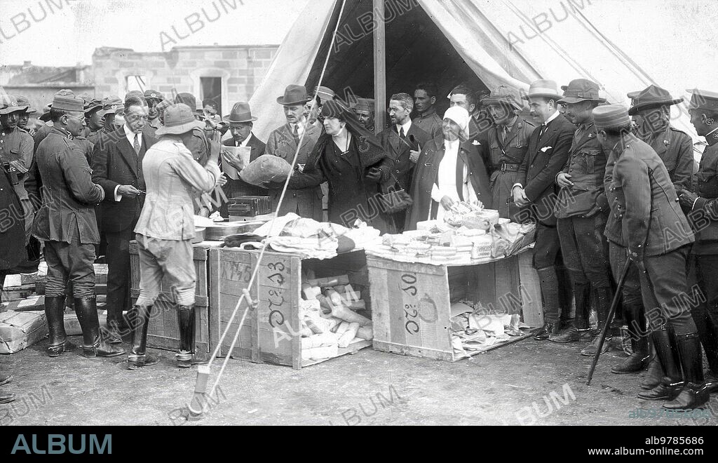 21 noviembre 1921. Melilla. La comisión de Valladolid en monte Arruit. Su alteza el infante D. Alfonso (1), la duquesa de la Victoria (2), y la marquesa de Cavalcanti (3), con el alcalde de Valladolid (4), Repartiendo los Obsequios de dicha ciudad A los Soldados del regimiento de Farnesio.