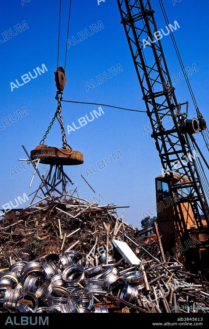 A giant crane-mounted electromagnet is used to move a pile of iron and steel items at a scrap yard in Carson, California.
