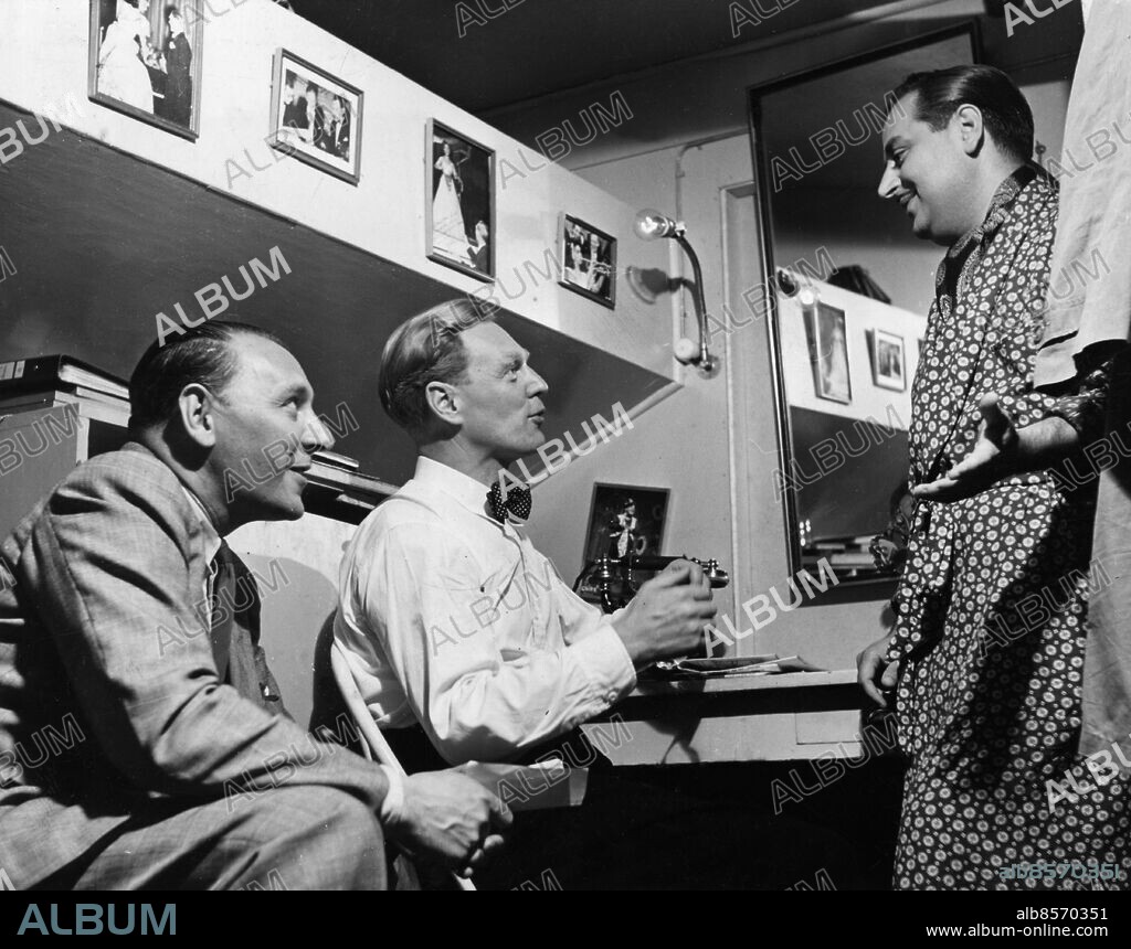 ARKIV STOCKHOLM 19500704.. Chinateaterns båda chefer Eigil Svan (t.v.) och kapellmästare Eskil Eckert-Lundin har en överläggning i logen med sångaren Dario Moreno i mönstrad sidenmorgonrock.. Foto: Sören Hoffman / SVT / Kod: 5600 . Bild publ. i RiR 29/50. Reportage publ. i RiR 29/50 inför radioprogrammet "Varieté!" som sändes 1950-07-21.. RiR sv/v . Mapp: Chinavarietén Numrerade kuvert 9201.