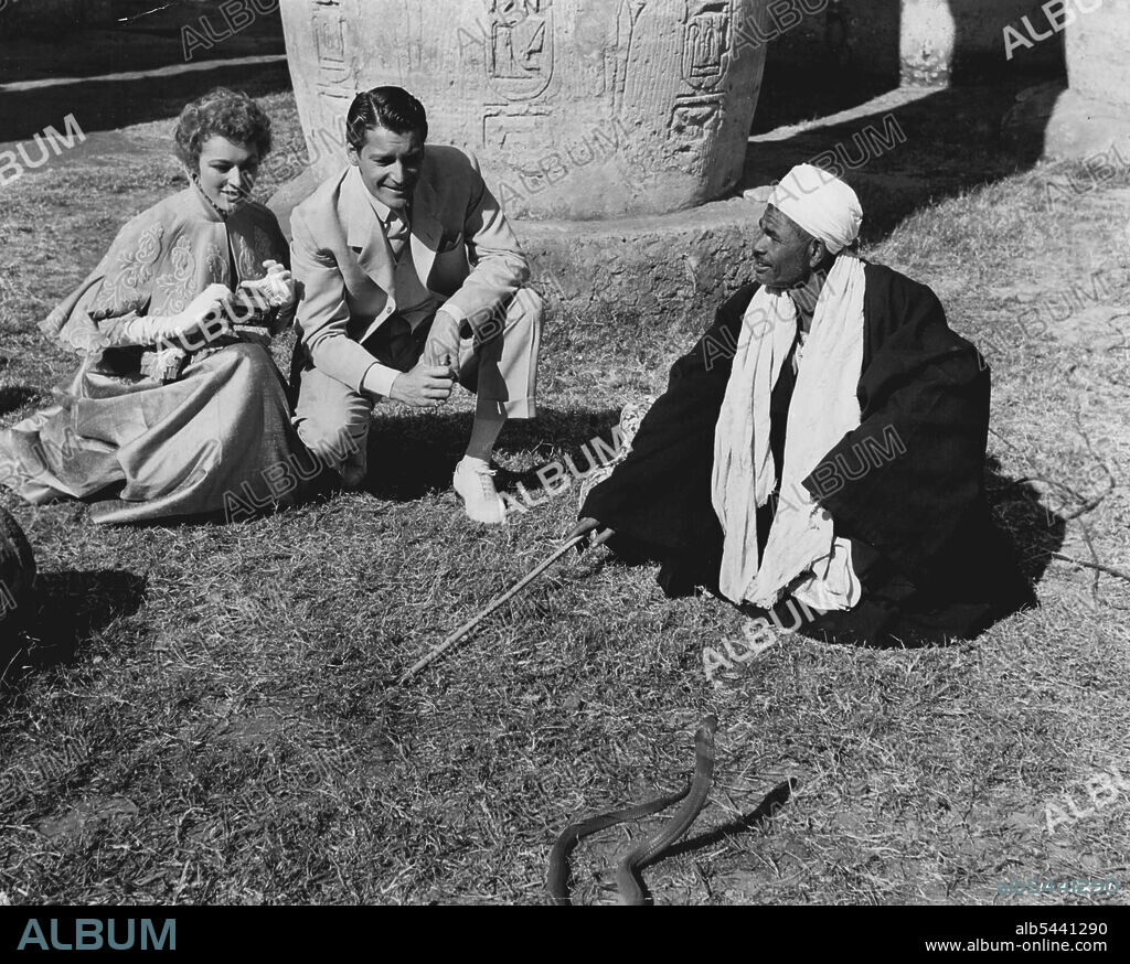 Egyptian Scenes... Between scenes of M-G-M's "Valley of the Kings" in Egypt, Eleanor Parker and Carlos Thompson look on as a local snake charmer in Luxor puts his pet cobra through his daily exercises. Robert Taylor co-stars in the exciting adventure film, most of which was made in Egypt. Robert Pirosh directed. July 3, 1954.
