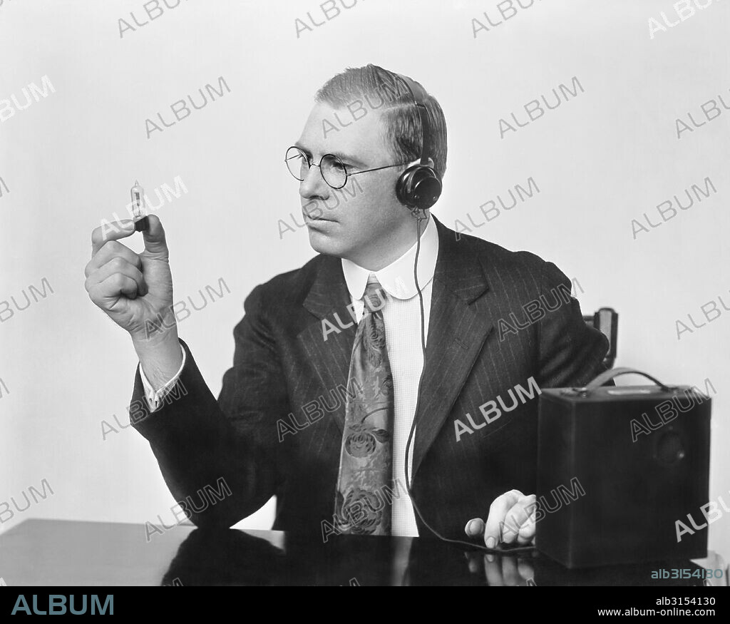 United States:   c. 1926 Inventor Earl C. Hanson holding the the peanut vacuum tube that he used in patenting the first vacuum tube hearing aid called the Vactuphone.