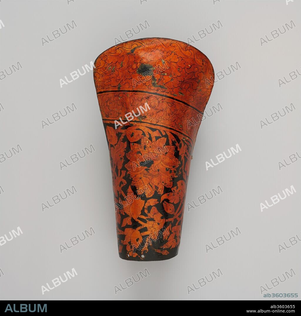 Forearm Guard for the Left Arm. Culture: Tibetan or Mongolian. Dimensions: L. 12 1/4 in. (31.1 cm). Date: possibly 15th-16th century.
The ornament on this arm guard is very similar to that seen on Tibetan horse armor, but it is larger in scale and its style is bolder. Like other arm guards of this type, its decoration consists of gold leaf covered with an orange-toned shellac and painted with a black pigment, with a clear shellac glaze overall. All known examples of Tibetan forearm guards appear to be for the left arm, suggesting that they were never made in pairs but were used on the left arm only. There are two basic types. One has applied iron struts, like those on Tibetan shields and furniture, often with ornamental piercings. The second type, shown here, has no applied iron fittings. Instead, the leather surface is entirely covered with varnished and gilded decoration. The same style and technique of decoration is also found on Tibetan bow cases and quivers.