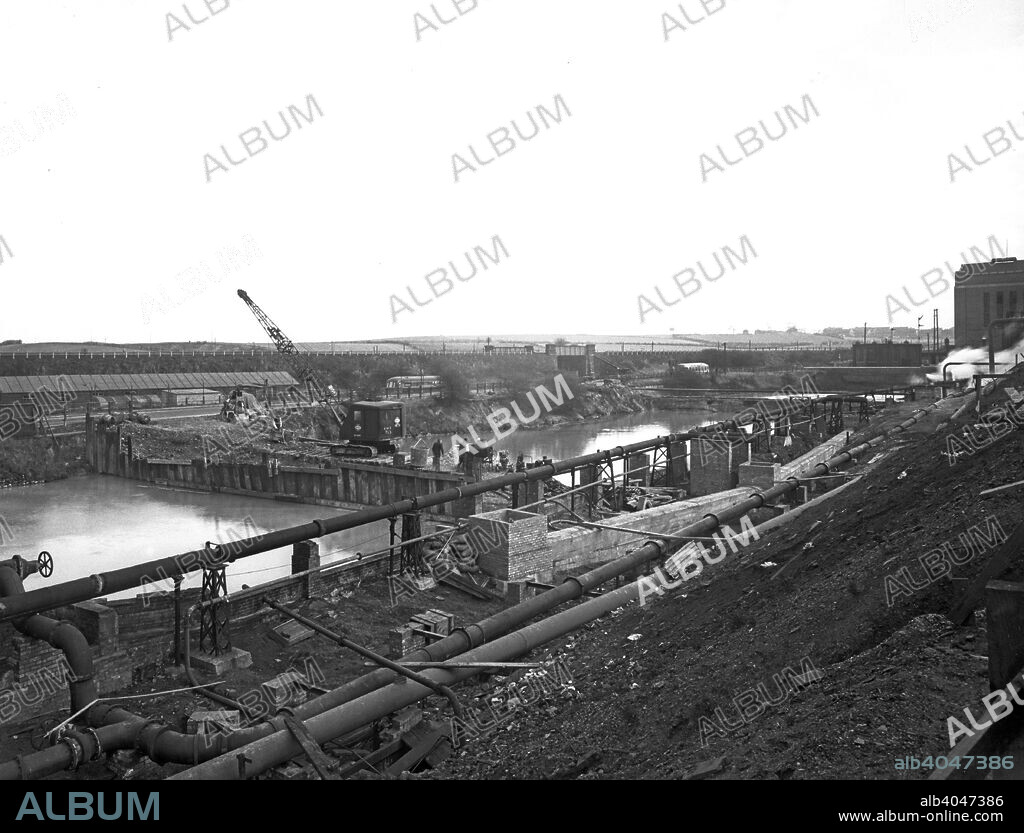 Construction of the reservoir, Manvers Main Colliery, Wath upon Dearne, South Yorkshire, November 1955. Manvers was sunk on land near Rotherham belonging to Earl Manvers in in the late 1800s and this was followed by the second shaft, sunk between 1900 and 1901. A third shaft was added later. Manvers was the regional headquarters for British Coal and the also housed laboratories. The site also included the Manvers coking plant which was at one time the largest industrial site in Europe. The coking works closed in 1981 with the colliery closure following a few years later on 25 March 1988.