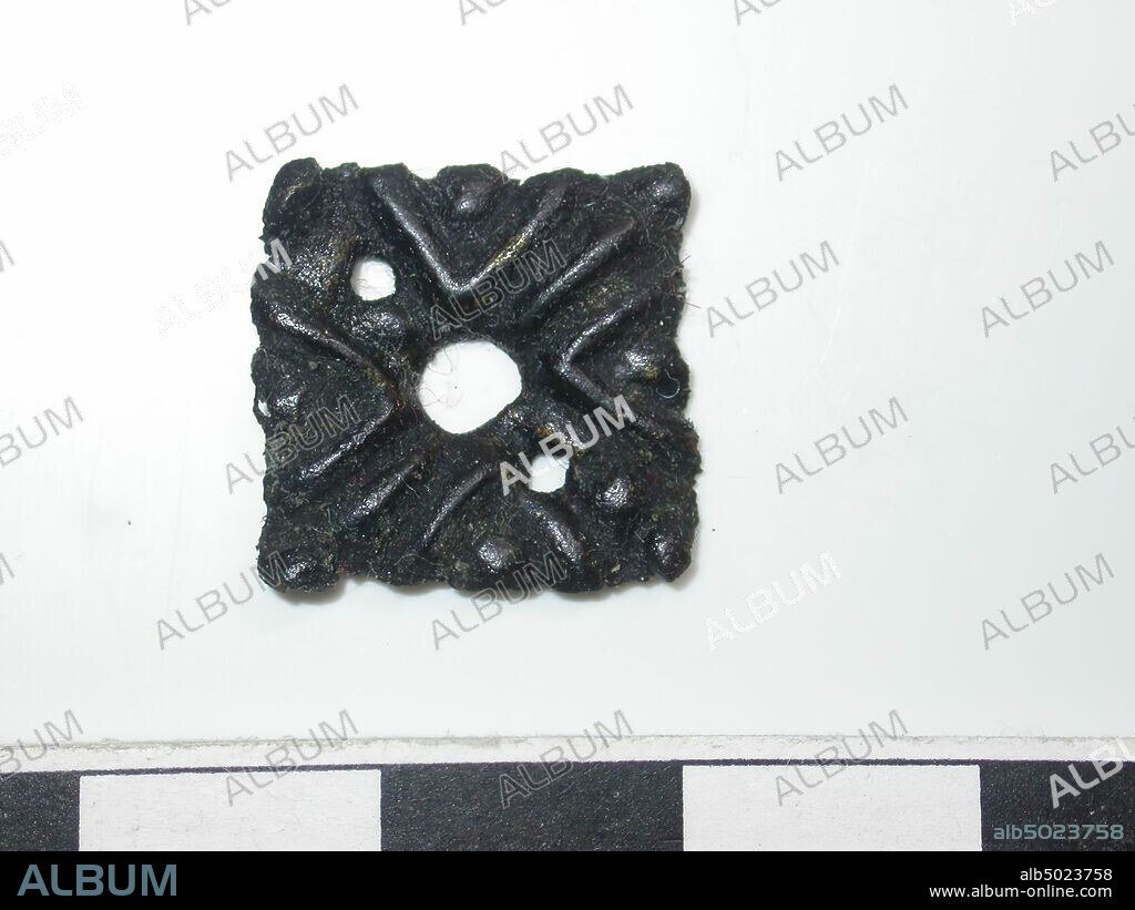 Square shape, dark with gold-colored spots (copper alloy). Square shape with a hole in the middle. Diameter hole is 0.3 cm. 2 diagonal stripes across the surface. Surface decorated with lines and pearls. There are 2 small holes in the surface. Back is hollow. No confirmation visible., Belt stroke, metal, copper alloy, H: 1,5 cm, W: 1,5 cm, D: 0,15 cm, end of the 14th century 1350-1400, Netherlands, Zeeland, Hulst, Verdronken Land.