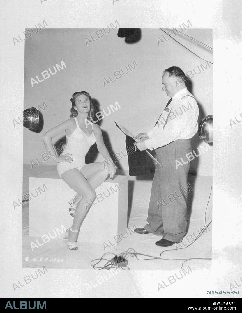 The Petty Girl And Her Creator -- Famed magazine artist George Petty arrived in Hollywood from New York to make sketches of actress Joan Caulfield, who will play the title role in Columbia's "***** The Year" comedy drama based on the Petty drawings. "Miss Caulfield is the ideal choice for the part", the artist declared, "and she's a perfect model". Robert Cummings will co-star with her in the film. April 5, 1950.