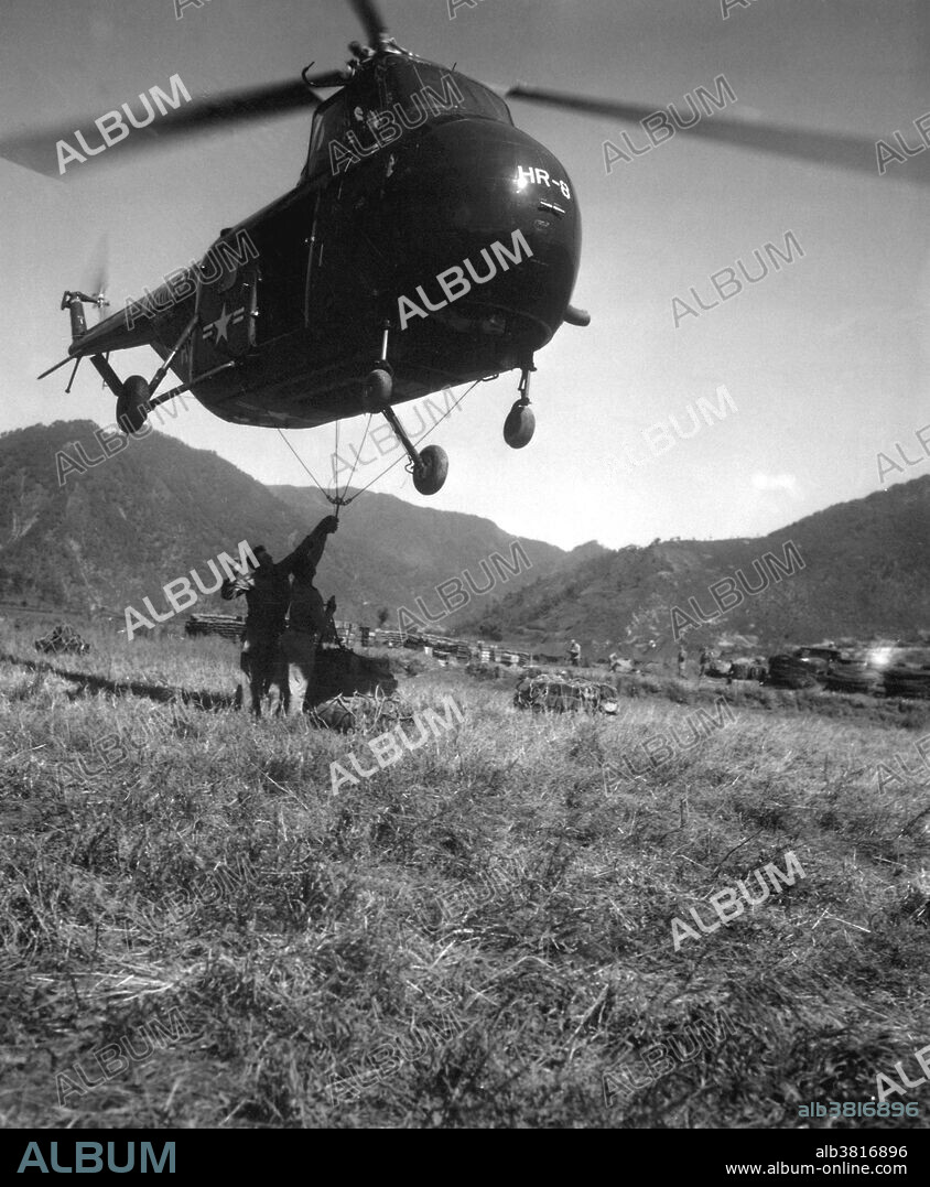 Captioned: "An HRS-1 (United States Marine Corps version of the HO4S for eight troops, 60 built) Sikorsky helicopter hovers close to the ground while Marines hook a cargo net loaded with 1,000 pounds of supplies for transportation to the front 12 miles away." On June 25, 1950, the Korean War began when soldiers from the North Korean People's Army crossed the 38th parallel, the boundary between the Soviet-backed Democratic People's Republic of Korea to the north and the pro-Western Republic of Korea to the south. This invasion was the first military action of the Cold War. By July, American troops had entered the war on South Korea's behalf. After some early back-and-forth across the 38th parallel, the fighting stalled and casualties mounted with nothing to show for them. Meanwhile, American officials worked to fashion some sort of armistice with the North Koreans. The alternative, they feared, would be a wider war with Russia and China. In July 1953, the Korean War came to an end. 5 million soldiers and civilians lost their lives during the war. The Korean peninsula is still divided today. Photograph credited to Master Sergeant Ed Waite, USMC, circa 1951.