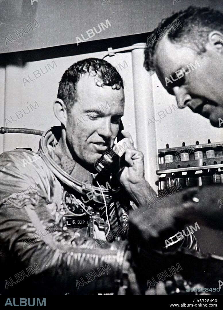 Congratulations Astronaut Leroy Gordon Cooper receives telephoned congratulations from President Kennedy following completion of his 22-orbit flight in the Faith 7 spacecraft May 16. Dr. Richard Pollard (right), head of the medical team aboard the prime recovery ship USS Kearsarge in the Pacific, assists the Astronaut in removing his space suit.