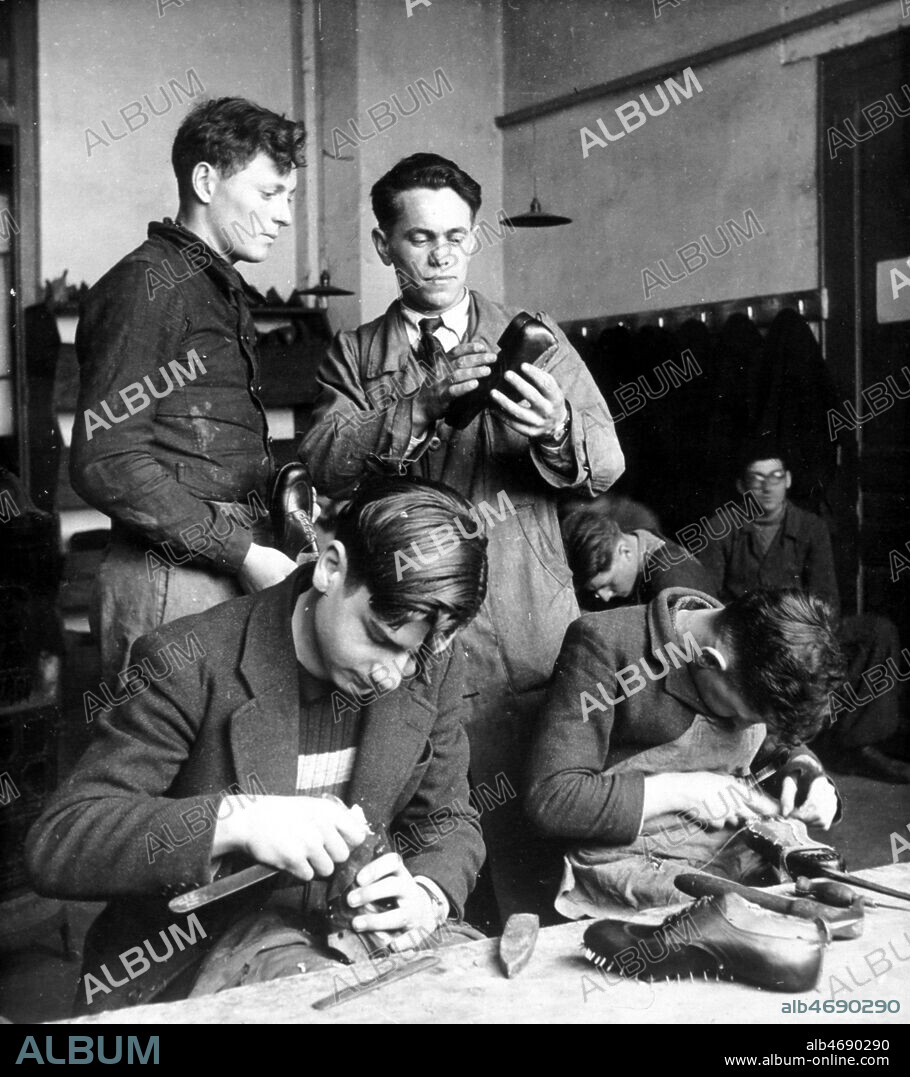 Ecole de cordonnerie de Romans. Le moniteur examine le travail d'un apprenti. Photographie d'actualite prise le 26/11/1943. Credit : Collection KHARBINE-TAPABOR.