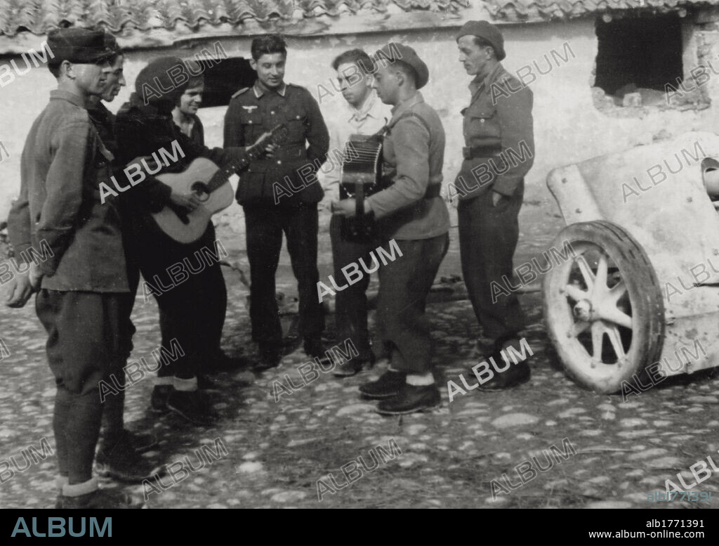 German and Romanian soldiers listening to music. Two soldiers playing accordion and guitar surrounded by brothers in arms, at a Romanian-German base near Kuban River. Russia, May 1943.