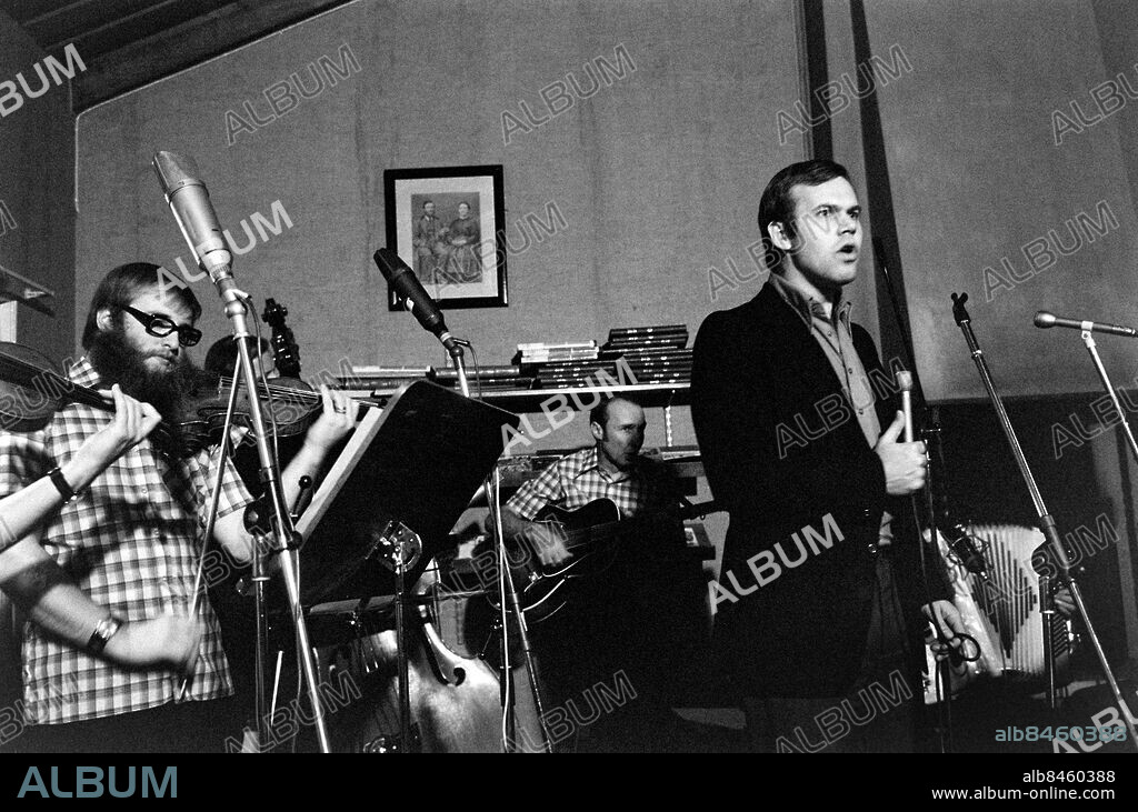 VÄRMLAND HÖLJES 1973-11-23. Reportage inför LIVAT I FINNSKOGARNA Radioprogram. Sänt första gången 1974-01-09. I ett värdshus i Höljes spelas programmet in med Ransäterspöjkera som husband. Här ses programledaren Per Eric Nordquist framför Ransäterspöjkera. Foto: Bo-Aje Mellin / RiR / SVT / Kod: 5600 Reportage publ. i RiR 2/74 sid. 14-16. RiR 21054 sv/v neg  Finnskoga Wärdshus persons: PER ERIC NORDQUIST sites: HÖLJES;SVERIGE;VÄRMLAND.