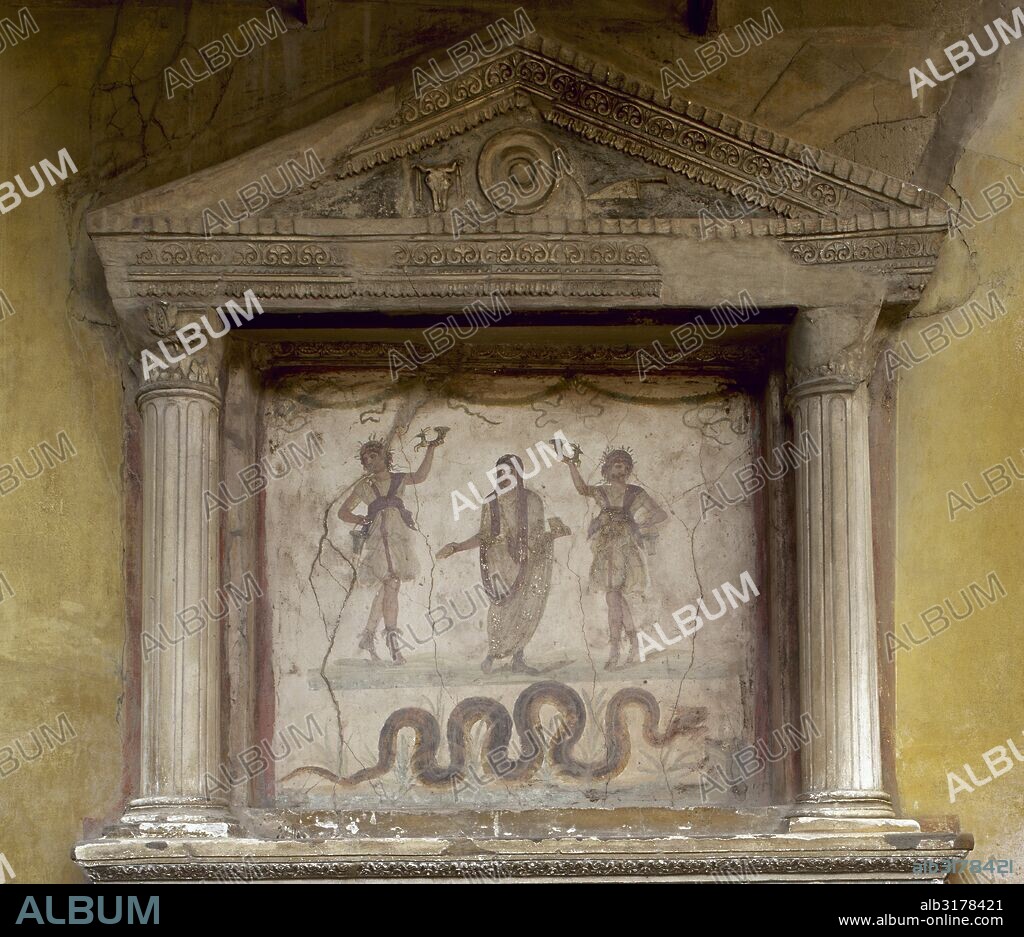 LARARIO TEMPLETE de la Casa de los Vettii. Dos Lares, sosteniendo un ritón, flanquean a un genio con un cuenco de libación y una caja de incienso, con la cabeza cubierta para un sacrificio. La serpiente, asociada con la prosperidad, se acerca a un altar. El tímpano muestra una patera, una calavera de buey y un cuchillo sacrificial. Pompeya. La Campania. Italia. decorado con frescos, donde se representa al GENIO del "Pater Familia" entre dos lares (dioses protectores). Bajo sus pies, la gran serpiente "Agathodémones", que apaga su sed con las ofrendas. POMPEYA. La Campania. Italia.