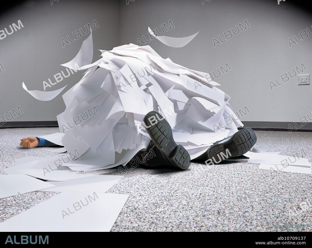 Overworked businessman buried under a pile of paperwork.