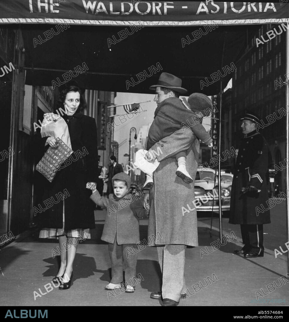 From A Cold Water Flat To The Waldorf -- Richard Earl Cox Carrier his sleeping 1½-year-old Son, Richard, Jr., As he, his wife Eleanor, and their other son, Jimmie, 2½, arrive at the Waldorf-Astoria Hotel, New York, March 14. Cox moved his family into a $12.60 a day room at the Hotel, insisting he would pay $4 of the monthly bill. The remainder. He said, would be sent to Mayor O'Dwyer because the city had not providing the Coxes with quarters in a veteran's housing project. The family was living in a $16 a month cold water flat in Brooklyn. March 14, 1948. (Photo by Associated Press Photo).