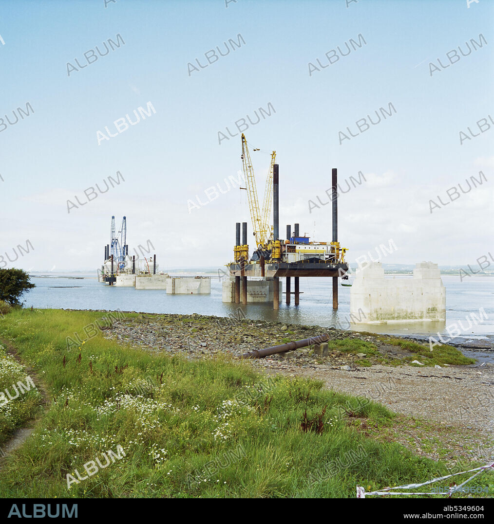 JOHN LAING PLC. A view of the construction of the Second Severn Crossing, showing cranes on platforms and concrete caissons installed in the River Severn. The Second Severn Crossing took four years to build and was a joint civil engineering project between Laing Civil Engineering and the French company GTM. The work started in April 1992 and the opening ceremony later took place on 5th June 1996. The crossing is a cable-stayed bridge which stretches over 5000 metres across the River Severn, 3 miles downstream from the Severn Bridge which opened in 1966.