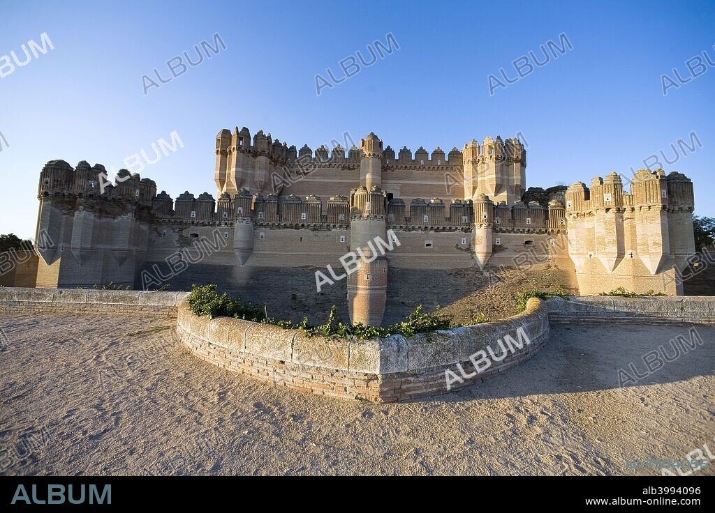 The Castillo de Fonesca (Coca Castle), Coca, Spain. Coca Castle was erected by Moorish builders in the mid-15th century for Bishop Alfonso Fonseca, archbishop of Seville and lord of Coca and Alaejos. It is a mixture of Moorish and military architecture. It is built entirely of brick, the material characteristic of the Mudejar style, laid in decorative patterns. It has a square ground plan, a moat and three walled enclosures. At the corners of the walls, are massive polygonal towers, which in turn have defensive turrets. The central structure of the castle also has tall polygonal corner towers and round towers along the sides. The interior is very luxurious and lavish and maintains its Mudejar decoration.