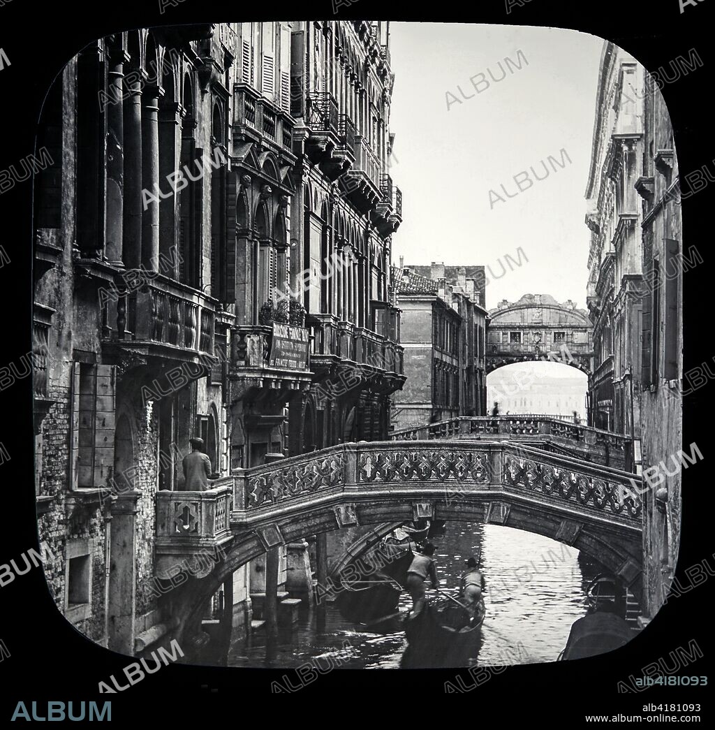 Magic lantern slide circa 1900.Victorian/Edwardian.Social History. The Beauties of Venice,photographs created in 1888 Joseph John William ACWORTH  F.I.C., F.C.S.J. The Beauties of Venice . Along the Canal leading to Bridge of Sighs. This view shows us a series of those ornate marble bridges spanning the Palace Canal, and connecting the various 'calli,' or narrow streets, on both sides of it. Right and left we get a good idea of the style of architecture of a large proportion of the habitations of Venice. They are substantially built, and for the most part when Venice was enjoying more fortunate  times. Â·' Those days are gone, but beauty still is here' [B] In the distance we see the other side of the Bridge of Sighs,and the open lagune beyond.