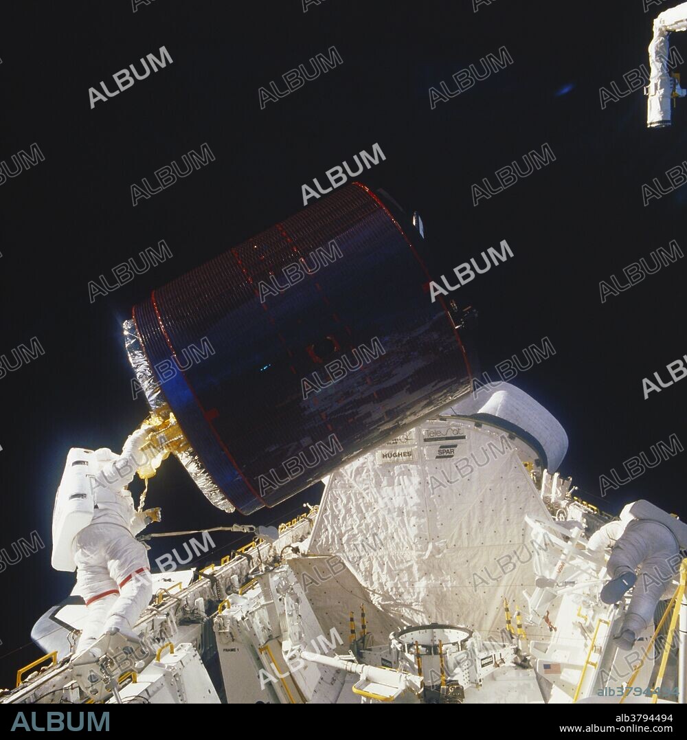 Astronaut Joseph P. Allen, (left), tethered to the orbiting Discovery, holds onto the Palapa B-2 Satellite while Dale Gardner returns the used "stinger" device to its stowage area; STS-51-A, (11/8/84-11/16/84).
