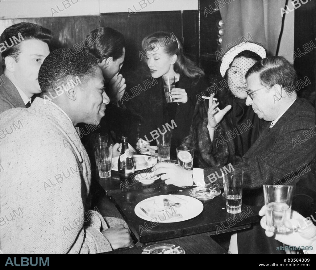 Orig. bildtext... COCKTAIL PARTY AT ST. GERMAIN FOR PARTICIPANTS IN SARTRE FILM A cocktail party was held at St. Germain des Pres, in Paris, last night to celebrate the commencement of the filming of Jean-Paul Sartre's play The respectful prostitute. Among those who joined in the party with Sartre were: Simone Berriau, who directs the french author's plays at the Paris theatre Antoine, Marcel Magliero, who will direct the Respectful prostitute, and the stars of the film; Barbara Laage, Yvan Desny, and the american negro Walter Bryant. Photo shows: Celebrating the commencing of the filming of Sartre's play the Respectful prostitute at St. Germain des Pres last evening, from left to right: Walter Bryant, Yvan Desny, unidentified, Barbara Laage, Simone Berriau and Jean-Paul Sartre. Anm. Filmen La putain respectueuse hade premiär 1952 J P Sartre: Nobelpriset i litteratur 1964 Skådespelare Samtal Flor Författare Profiler CD190 persons: Walter Bryant ;Yvan Desny ;Barbara Laage ;Simone Berriau ;Jean Paul Sartre sites: FRANKRIKE ;PARIS.