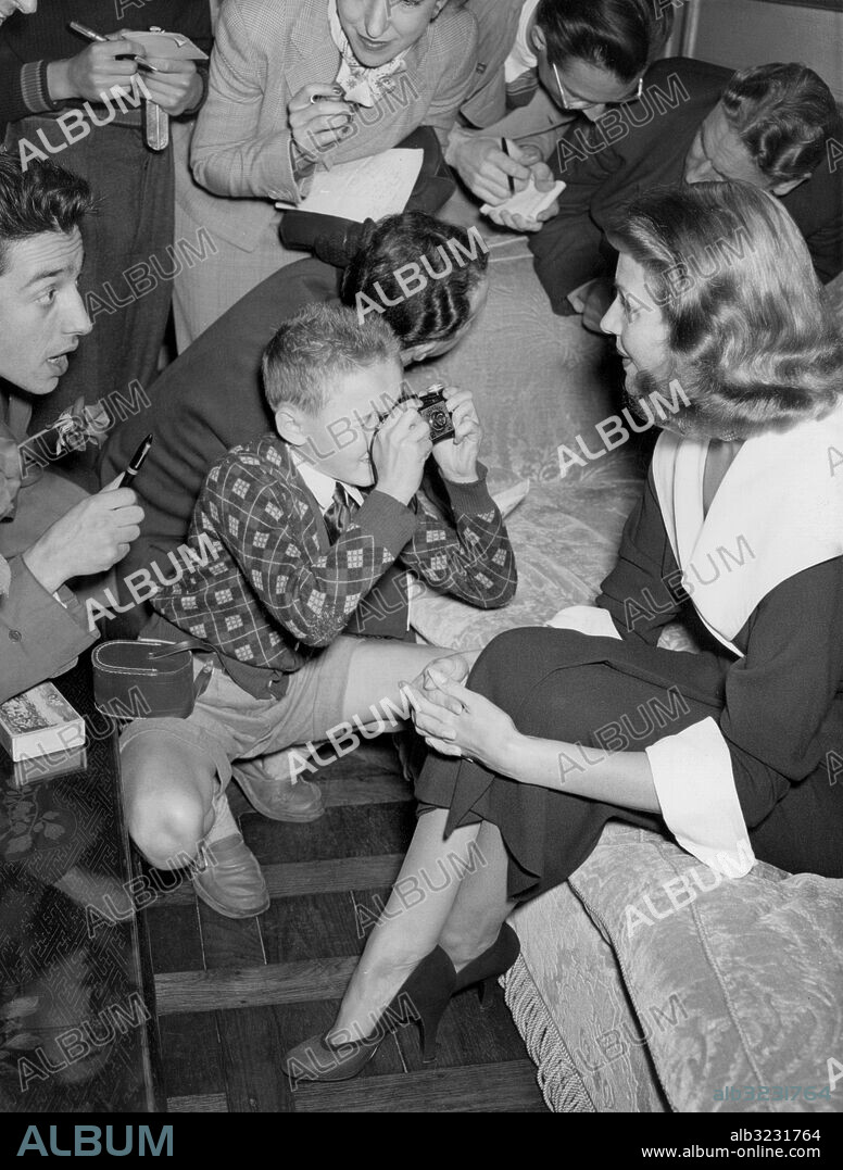Orig. bildtext... ALY AND RITA HOLD PARIS PRESS CONFERENCE Prince Aly Khan and his wife, Hollywood actress Rita Hayworth, held a press conference this afternoon at Aly Khan's villa at Neuilly-sur-Seine, just outside of Paris. Rita said that she had nothing to say as she is on a holiday and has made no plans, except that she is returning to the United States in February to make a picture, however, the film star said that she had dropped divorce proceedings for the present. The prince said that he would let Rita answer the reporters questions, but said that he intended to remain in Paris for only a month or six weeks, and then visit the Middle East on his father's business. PHOTO SHOWS: A small French boy, who managed to crash the press conference which Aly Khan and Rita Hayworth held this afternoon, taking a snapshot of the glamourous Rita as journalists continue to ply Rita with questions. Anm. Skådespelare Intervjuer Journalister Fotografer Kameror Kameraväskor Trängsel Idoler Fans CD172 persons: Rita Hayworth sites: USA* ;FRANKRIKE ;NEUILLY-SUR-SEINE.