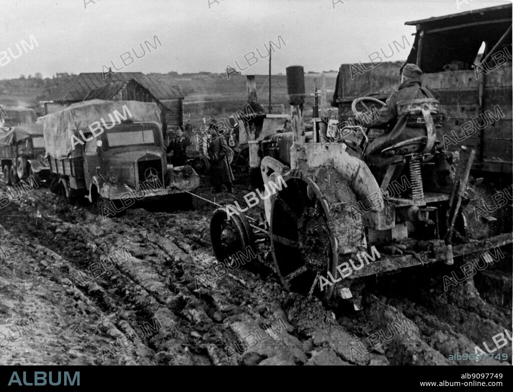 WW2: General "Mud" on the Eastern battle-front. Swampy terrain of Russia during the autumnal rains. German army lorries get stuck on a muddy road on the Eastern Front, have to be pulled out by a transport tractor.