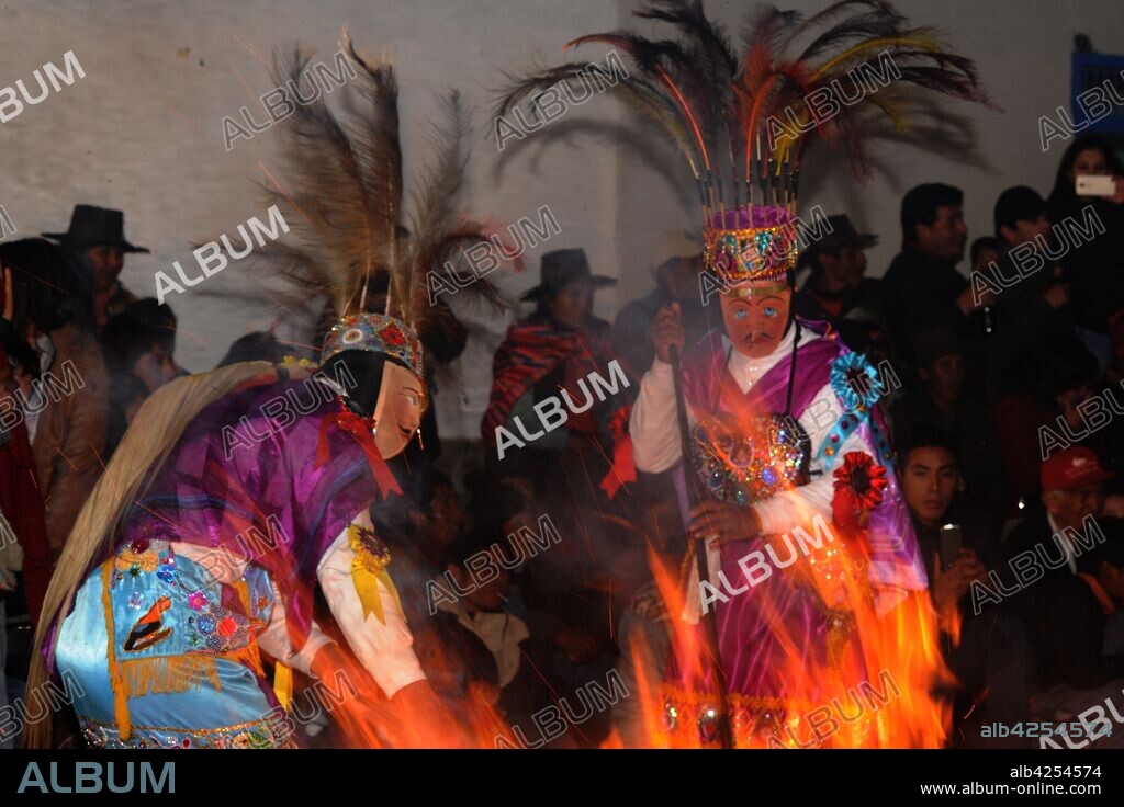 Characters in costumes wearing masks, with bonfire at the annual festival in honor of their patron saint, Mamacha Carmen at Pucartambo, Cusco, Peru. The Virgin Mary is carried in procession through the streets, preceded and followed by traditional dancers of several types, and many festival goers. Traditional dances of the festival include Chukchu, Ch'unchu, Qhapaq negro, Qhapaq Qulla and Saqra.