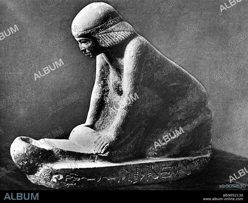 Egyptian woman grinding corn using a saddle quern. Egyptian tomb figure c 2,500 BC. Photograph c1910.