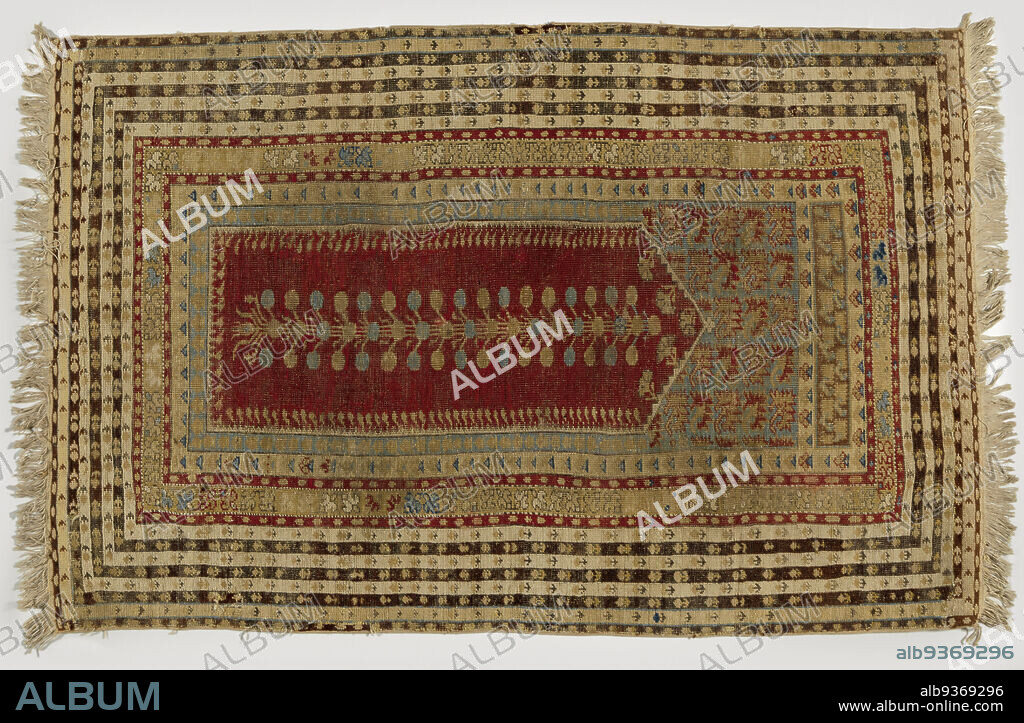 Prayer rug with one transverse panel, KULA, Prayer rug with one transverse panel, KULA. Center field: red mihrab with flat triangular gable, in which hangs a branched flower stem in blue and yellow. The swags are sky blue with straight rows of carnations. A narrow upper warp is in brown with carnations. Edges: multiple. The widest consists of seven stripes in white, purple, black and beige. The first inner hem is white, the second pale yellow and is encased in piping. Outside, only one such piping runs., Kula, 1800 - 1900, wool, height 182 cm × width 113 cm.