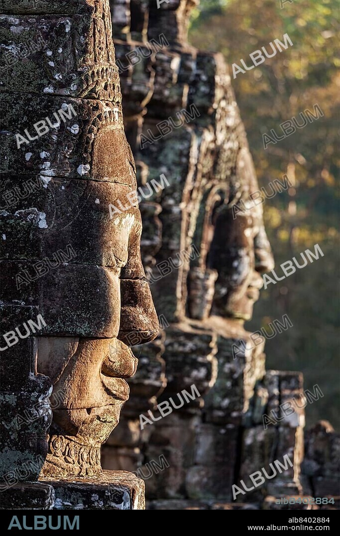 Ancient stone faces of Bayon temple, Angkor, Cambodia on sunset.