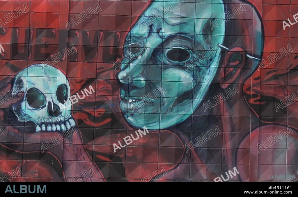 ilustracion de cara con máscara y calavera en la mano representando la escena de ser o no ser; graffiti mural, Plaza de las Glorias; Distrito San Martin, Barcelona en 2016.