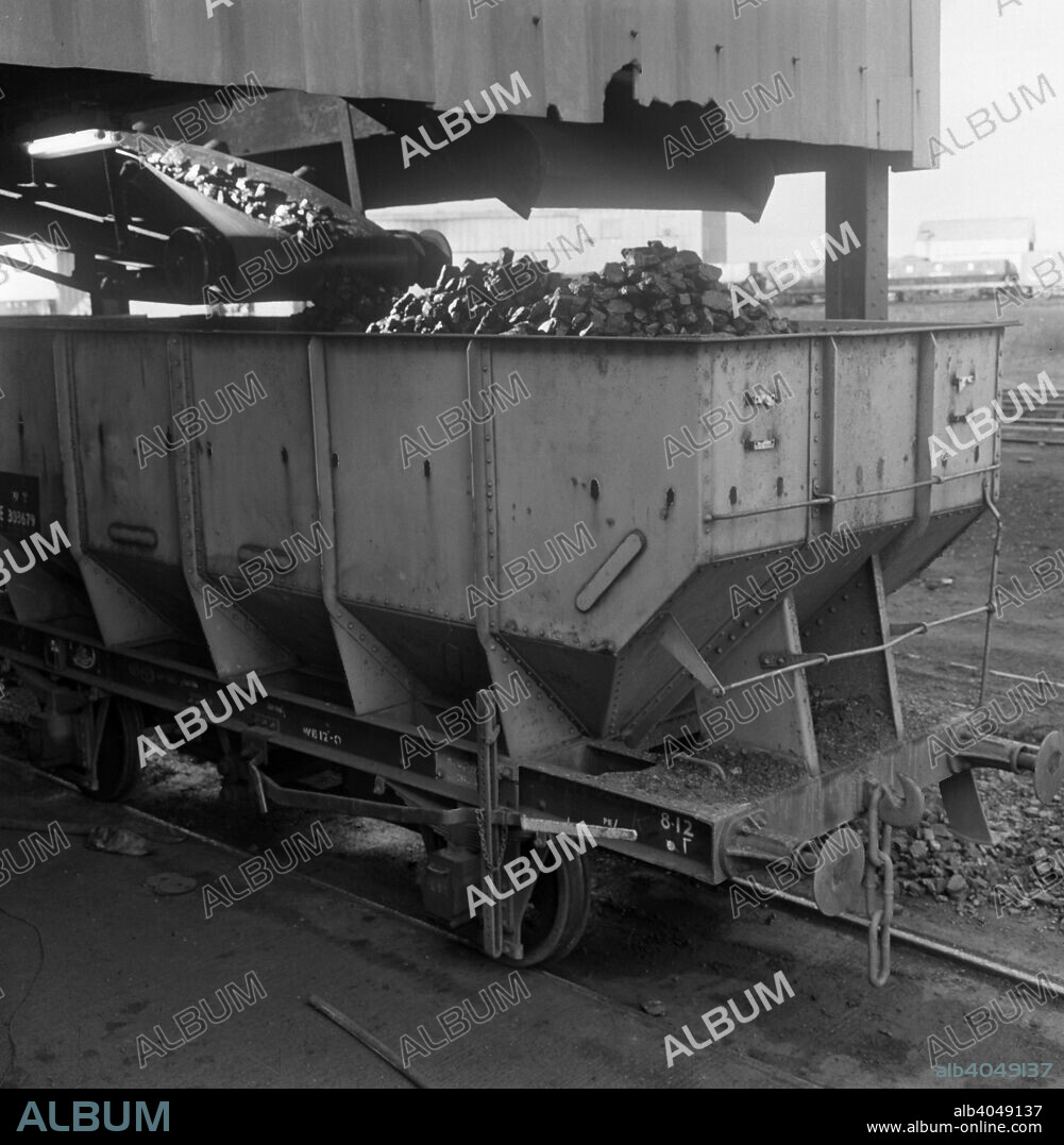 A rail truck being loaded with coal, Lynemouth Colliery, Northumberland, 1963. The rail system was vital to the coal industry to distribute its product. The photograph was commissioned by the National Coal Board (NCB) to demonstrate the process. The colliery opened in 1927 and eventually closed in 1994.