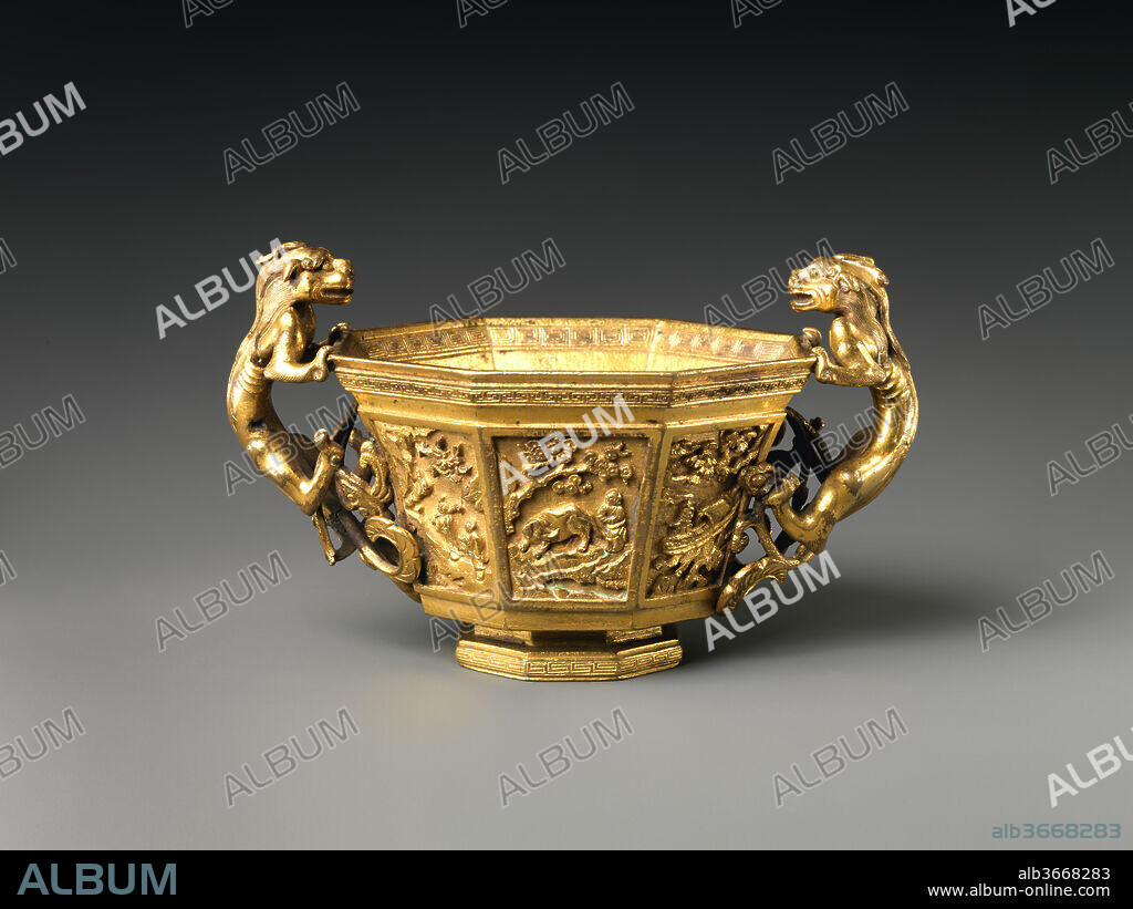 Octagonal cup with dragon handles. Culture: China. Dimensions: H. to handles 3 1/4 in. (8.3 cm); H. to rim (2 1/2 in. (6.4 cm); Diam. of rim 3 5/8 in. (9.2 cm); Diam. of foot 1 7/8 in. (4.8 cm). Date: 17th century.
This cup is extraordinary both for its design and fine casting. The octagonal shape has precedents dating back to the late 7th century when Sassanian silversmiths settled in the Tang dynasty capital of Chang'an and introduced this form into the Chinese repertoire. The twin dragon handles, a motif that can be traced back to the 13th century, remained a popular design in subsequent centuries in different materials, notably jade and rhinoceros horn. The powerful musculature and sinuous bodies of these leonine dragons enable the cup to be dated confidently to the 17th century. Likewise, the distinctive, intricately cast vignettes on the cup's eight facets also bespeak a late Ming date. Each panel presents a different legendary story. The style of these panels resembles carved lacquer, but is only rarely seen on bronzes. 
The narratives all relate to Daoist paragons of reclusion and liberated living--a fitting subject for a wine cup. One prominent scene highlights the efforts of a Confucian monarch to recruit one such worthy to serve in office. It illustrates how King Wen of Zhou is said to have personally invited the famous strategist and hermit Jiang Shang (1156-1107 B.C.) to become his chancellor while Jiang calmly continued to fish. The story vividly conveys the wish that men of talent be recognized and valued by the ruler.