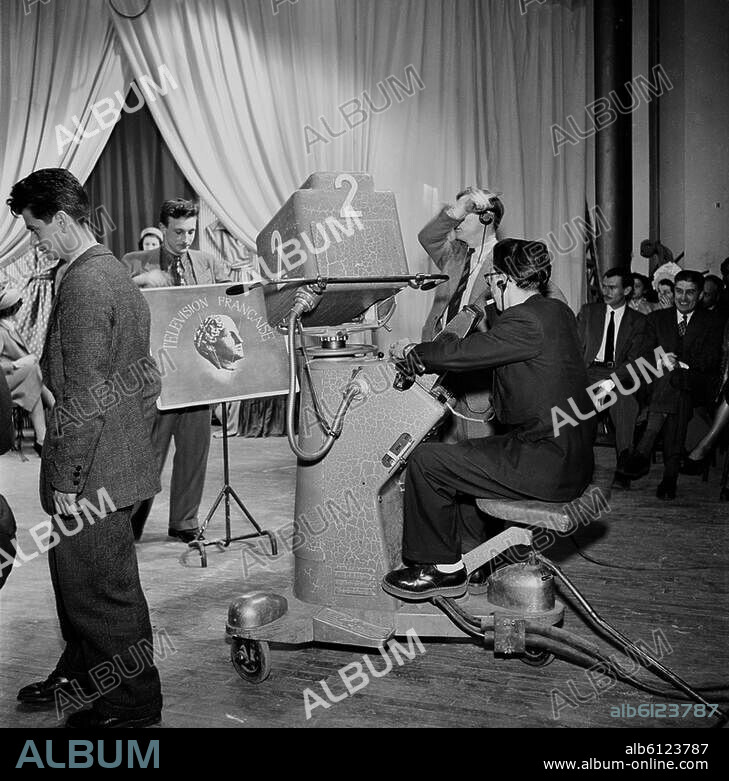 TV / Studio.-TV. Fashion show at the RDF (Radiodiffusion Française) studios in Paris, France, shown during the "La Femme chez elle" tv show. Camera and audience.-Photo, undated, before 1949.