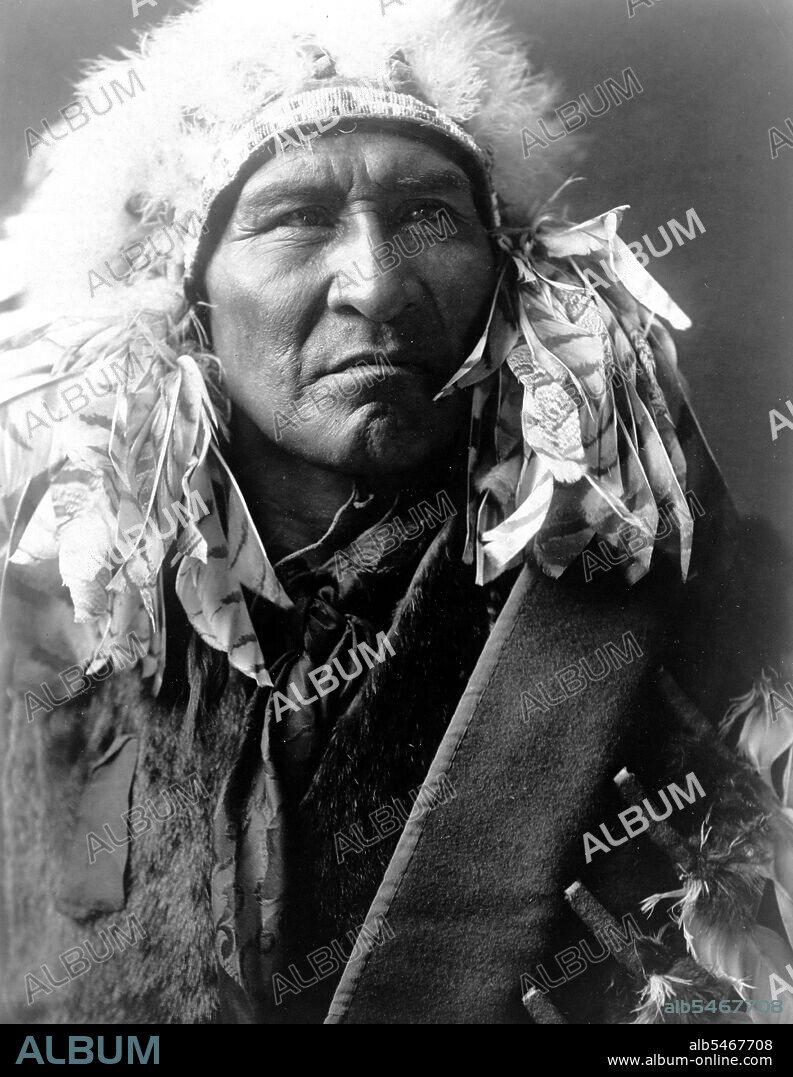 Edward S. Curits Native American Indians - Photograph shows Bread, an Apsaroke Indian, wearing a headdress circa 1908.