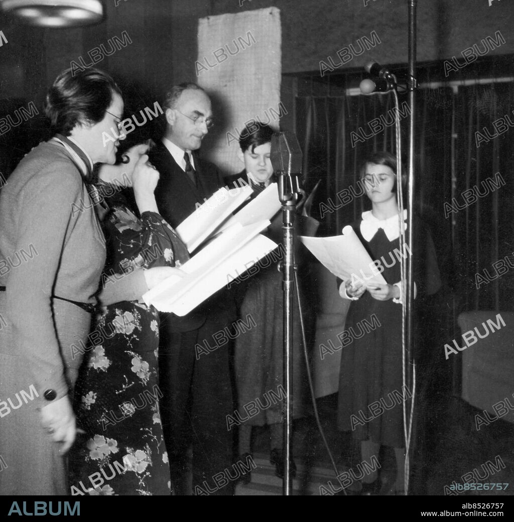 1936.. Anm. Studios Inspelningar Manus Publ. i RiR 2/36 35/37 35/38 37/55 Publ i Etermediernas bok Finrummet och lekstugan s. 80: Familjen Björck samlad framför mikrofonerna. Från vänster Frida Winnerstrand som makan och modern, Gull Natorp som hembiträdet Hulda, Olof Winnerstrand som familjens överhuvud samt Bill Jansson och Lisbeth Bodin som barnen. En rar och strävsam familj som tillsammans gjorde närmare etthundratrettio avsnitt i radio. O Winnerstrand, 1875-1956, svensk skådespelare. F Winnerstrand, 1881-1943, svensk skådespelerska. L Bodin, 1922-2007, svensk skådespelerska. G Natorp, 1880-1962, svensk skådespelerska. persons: GULL NATORP;BILL JANSSON;LISBETH BODIN;OLOF WINNERSTRAND;FRIDA WINNERSTRAND sites: SVERIGE.