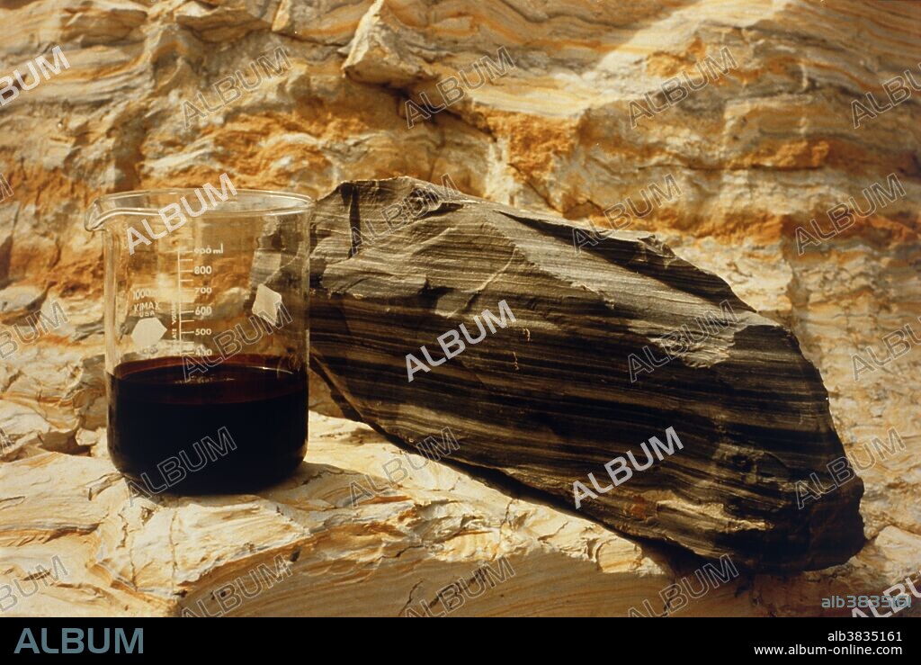 Block of oil shale (marlstone) and a beaker of the crude oil (kerogen) that is derived from it. Oil shale is a fine-grained rock that contains varying amounts of kerogen, an organic material. Heating or retorting (distilling) to 900 degrees F. yields a synthetic oil and gas. This specimen is from the Green River formation, a major U.S. deposit spread over the Colorado-Wyoming-Utah area.