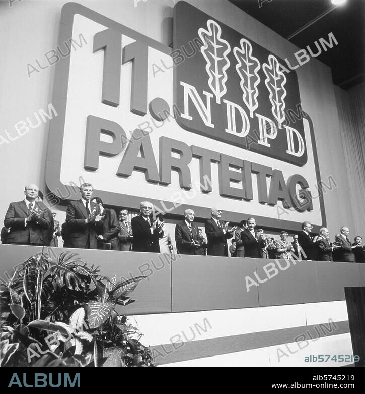 Deutschland / DDR / 11. Parteitag der Nationaldemokratischen Partei Deutschlands in Leipzig, Messehallen, 21.-23.4.1977. Blick auf das Präsidium mit dem Parteivorsitzenden Heinz Hommann (1. R., 5. v. l.) und Lothar Bolz (3. v. l.). Foto, April 1977.