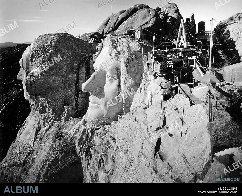Top view of Mount Rushmore during the carving. Mount Rushmore National Memorial is a sculpture carved into the granite face of Mount Rushmore near Keystone, South Dakota. Sculpted by Danish-American Gutzon Borglum and his son, Lincoln Borglum, Mount Rushmore features 60 foot sculptures of the heads of four United States presidents: George Washington, Thomas Jefferson, Theodore Roosevelt, and Abraham Lincoln. Construction on the memorial began in 1927, and the presidents' faces were completed between 1934 and 1939. Although the initial concept called for each president to be depicted from head to waist, lack of funding forced construction to end in late October 1941. Mount Rushmore has become an iconic symbol of the United States, and attracts over three million people annually. Photographed by Charles D'Emery, undated.