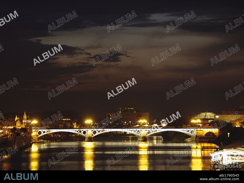 ANDALUCIA. SEVILLA. Vista nocturna del PUENTE DE ISABEL II, conocido también como Puente de Triana. Está situado sobre el RIO GUADALQUIVIR y fue construído entre los años 1847 y 1852 por los ingenieros franceses BERNADET y STEINACHER. España.