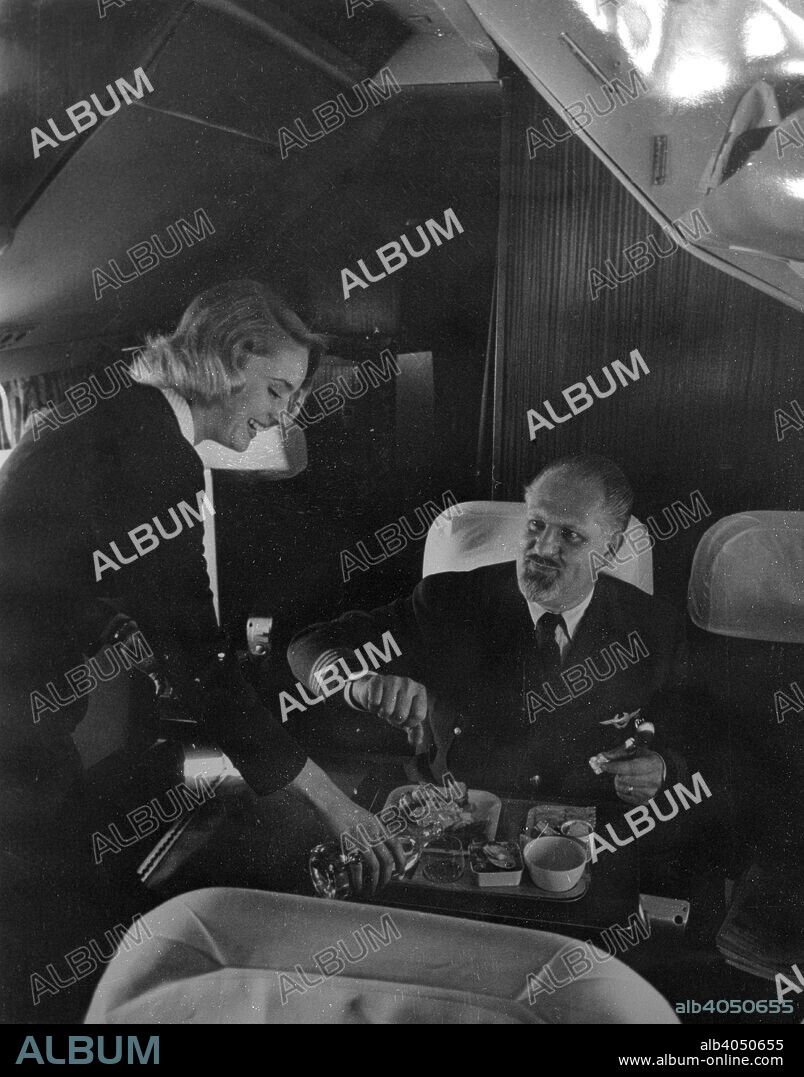 SAS stewardess serving on a flight, 1960. Scandinavian Airlines System (SAS), the flag carrier of Sweden, Norway and Denmark, was founded in 1946.