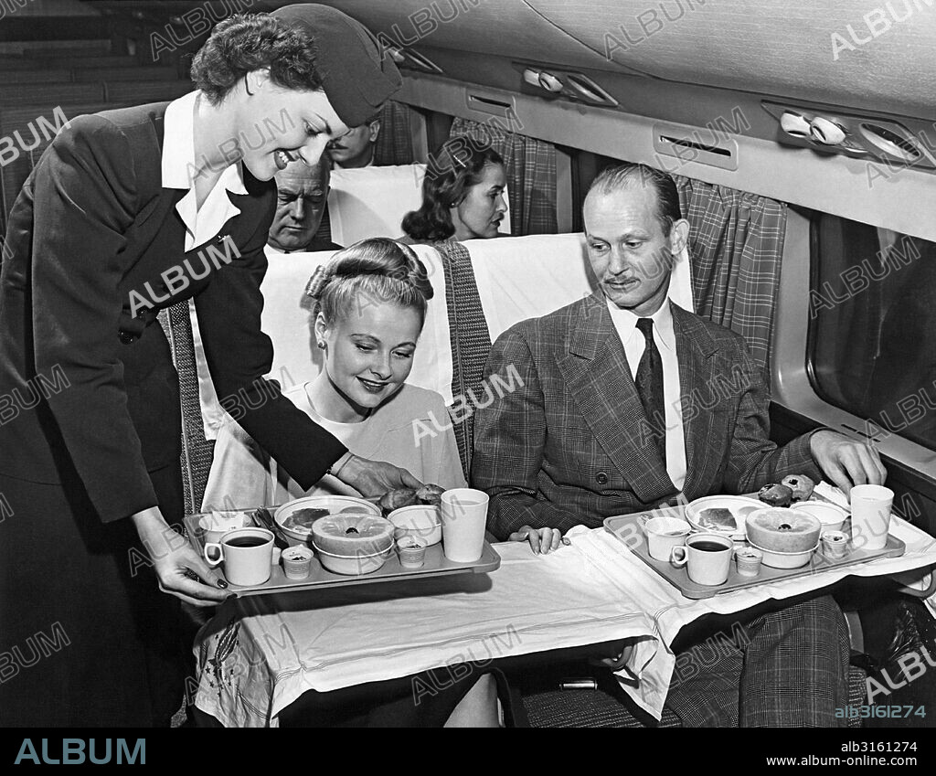 United States: c. 1958 A stewardess serves a meal to a couple on an American Airlines flight.