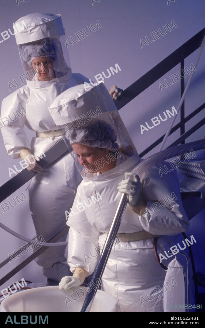 Workers in toxic isolation suits in granulating room of a pharmaceuticals manufacturing plant.