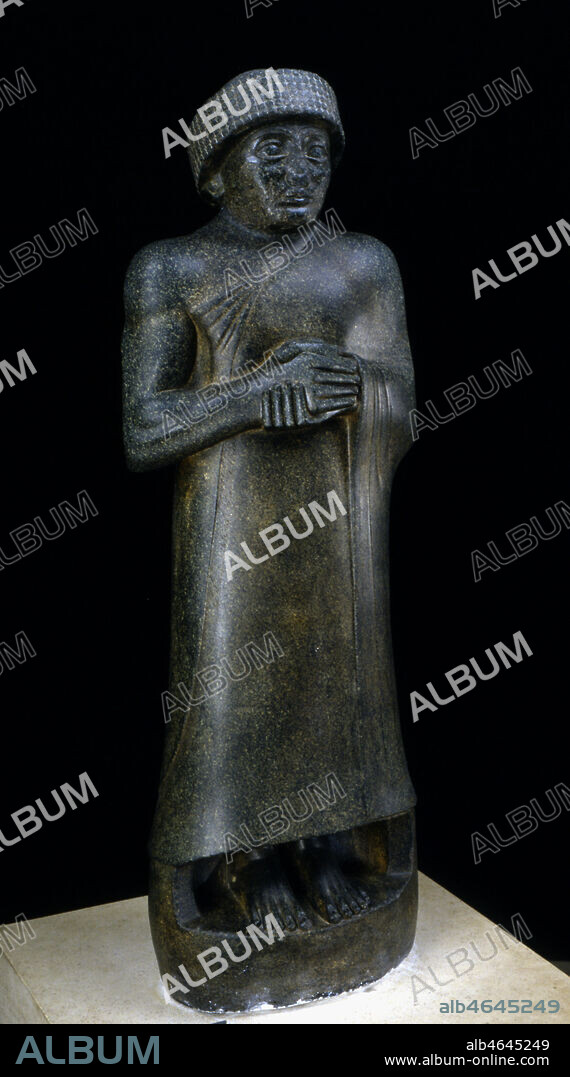 Statue du prince Gudea en prière. Diorite. Vers 2125-2110 av. JC. Provient probablement de la ville de Tello, ancienne Girsu, état sumérien de Lagash, au sud de l'actuel Iraq. La chute de l'empire d'Akkad sous les coups de l'envahisseur Guti, laisse un vide politique et culturel que l'état de lagash est le premier à combler vers 2100 av. JC. Le prince Gudea (2125-2110 av. JC) dont le nom signifie "l'appelé" en sumérien instaure une aire de prospérité, constituant des alliances avec les états voisins pour faciliter la réouverture des voies commerciales et restructurant la cité, dans ce que l'on a appelé une véritable "renaissance sumérienne". Il semble avoir résidé à Girsu, l'actuelle Tello, et a consacré une grande partie de son activité à la fondation de temples dédiés aux principales divinités du pays. Bien que ne possédant pas d'inscription, cette statue peut-être identifiée d'après les traits du visage comme une effigie de Gudea. Comme la plupart des statues de ce souverain, elle le représente dans le geste de la prière, debout devant la divinité. Le costume est l'habituelle robe-châle enroulée autour du corps et dégageant l'épaule droite, la tiare royale est à cette époque un bonnet cylindrique de laine bouclée. Les pieds sont nus, protégés par un pan de pierre descendant du vêtement qui soude la statue à son socle, de manière à la rendre indestructible.. La diorite, pierre royale depuis l'époque d'Akkad est une roche dure venue du pays de Magan (en Iran ou en Oman). Elle permet à l'artiste de jouer sur les volumes lisses et d'obtenir des contrastes dans le rendu des détails. Le volume général est fuselé et dynamique, s'effilant vers le haut. Pour le détail du visage, voir kh61283 bis. Credit : Larrieu-Licorne/Kharbine-Tapabor.