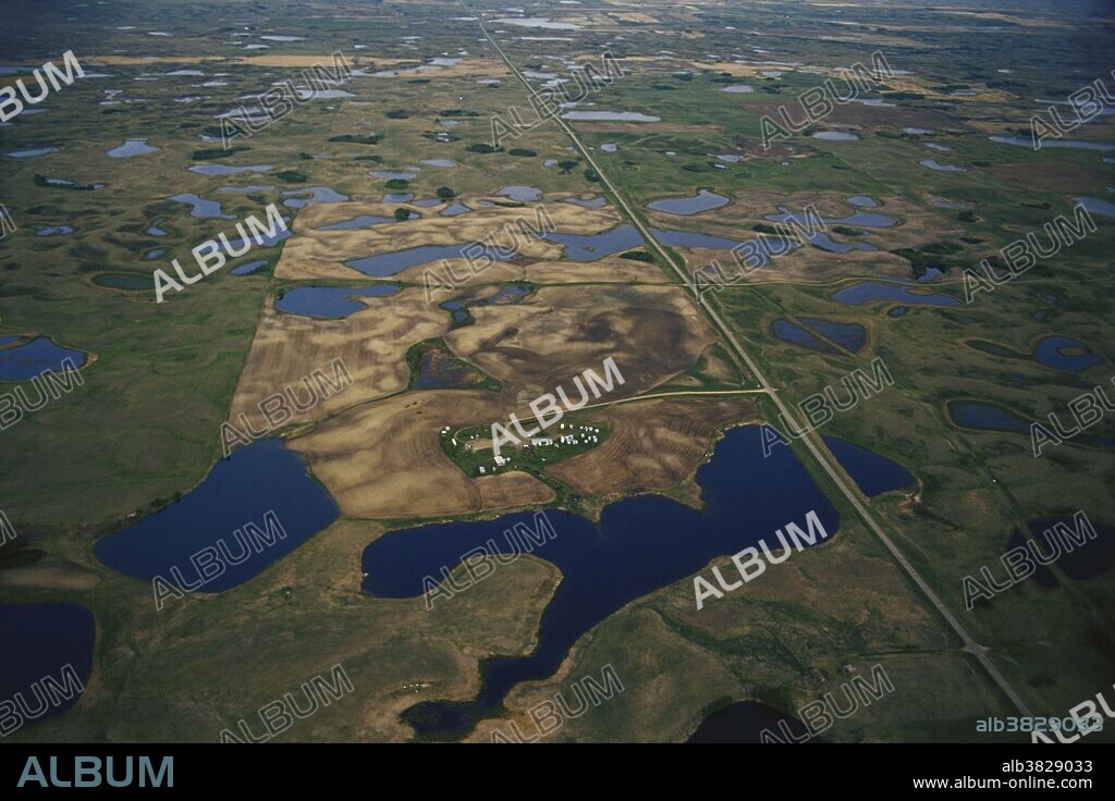 Aerial photo of the North Dakota prairie in May, with an abundance of prairie pothole lakes and a farm.