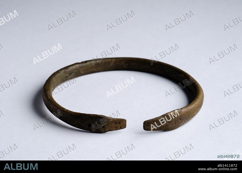Brazalete o pulsera de bronce en cuyo cierre aparecen representadas las cabezas de dos serpientes enfrentadas y decoración punteada. Diámetro 6, 7 cm Grosor 0,3 cm . ( Siglo V - VIII dc ) - Epoca Visigoda , procedente de la " Calle Victoria "- Yacimiento arqueológico de Complutum en Alcalá de Henares ( Madrid ). ESPAÑA.