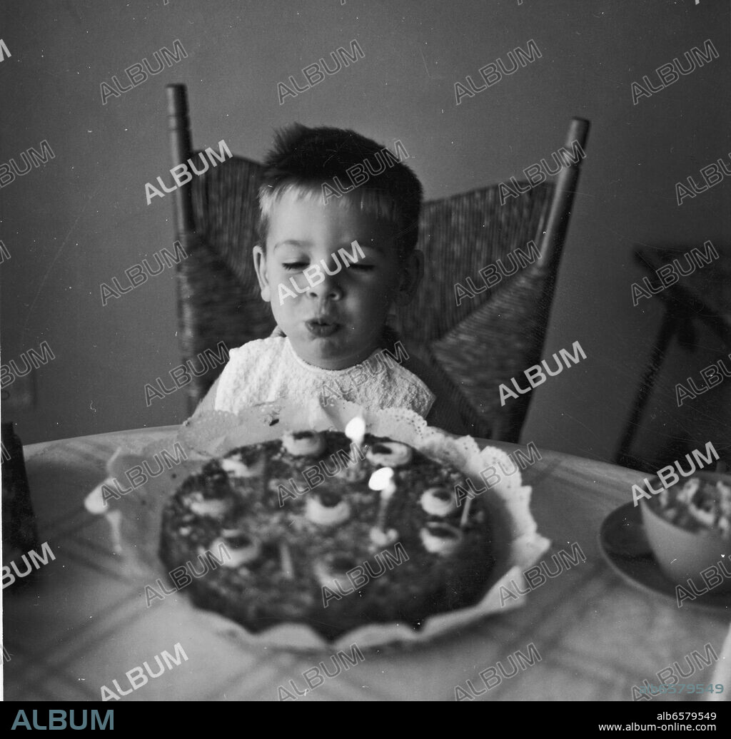 NIÑO DE DOS AÑOS SOPLANDO LAS VELAS EN SU CUMPLEAÑOS - FOTOGRAFIA BLANCO Y NEGRO - 1962.