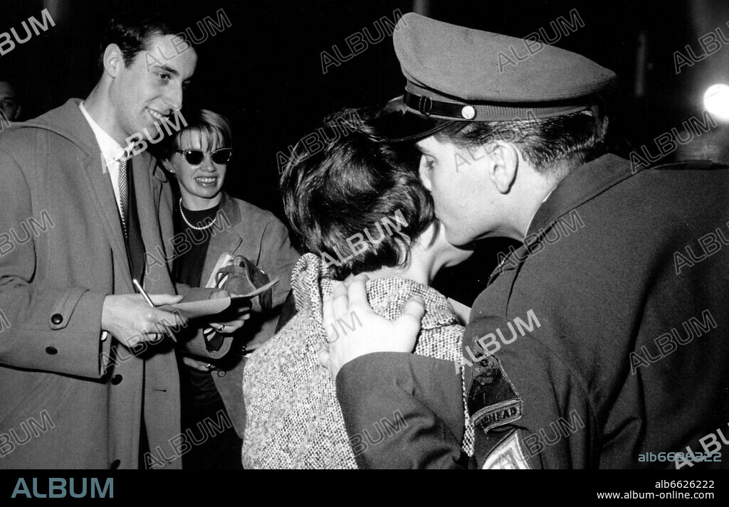 American teenager idol Elvis Presley (r) kisses one of his female admirers in front of journalists on the cheek on the 1st of March in 1960. The girl managed to enter the Ray barracks in Friedberg under the pretext of being a reporter, where the press conference on the occasion of the termination of Presley's military service took place. The American Rock'n Roll singer was stationed in Friedberg (Hesse) in the context of his military service in the US Army in the 1950s and will leave Germany from Frankfurt am Main in a military airplane on the 2nd of March in 1960. 01/03/1960