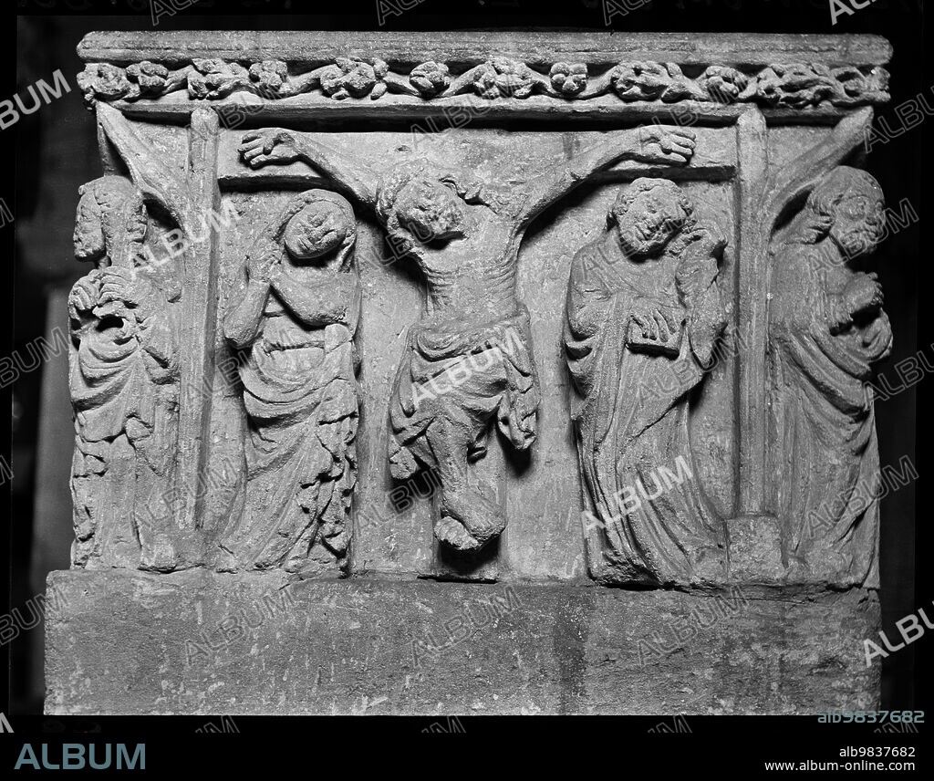 ETHEL BOOTY. Church Of The Holy Rood, Shilton, West Oxfordshire, Oxfordshire, England, 1940-1949. Detail of a panel in a 15th century square font in Holy Rood Church. Detail of a panel showing the Crucifixtion of Christ. The figure of Christ is on the cross in the centre of the panel, with a woman stood on his right, possibly Mary, and a man holding a book on his left. The scene is bordered with vertical supports and there is a robed figure stood on each corner of the font.