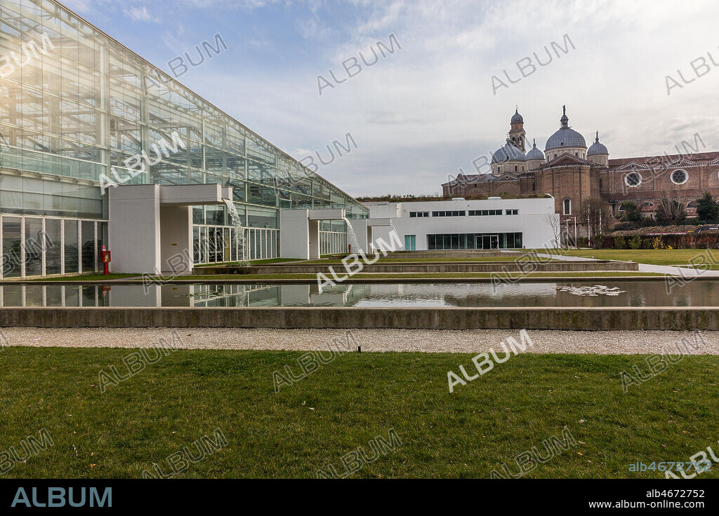Padova, the Botanical Garden: the big greenhouse of the Garden of Biodiversity. In the background, the Basilica of St. Giustina.