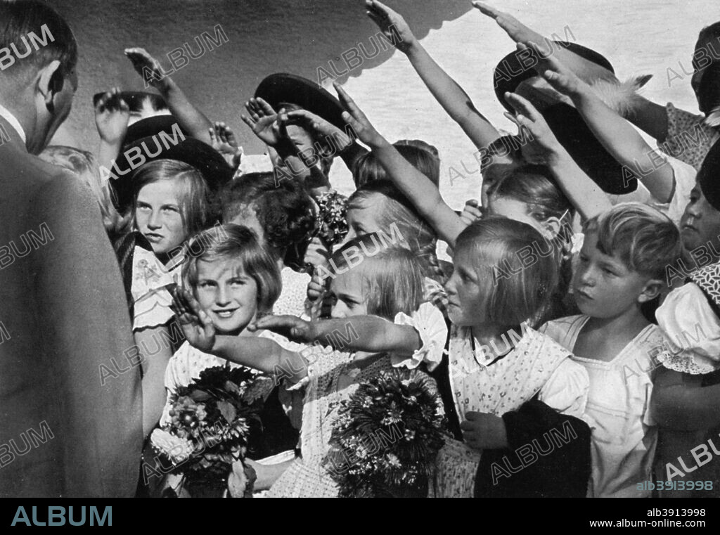 Adolf Hitler with a group of young children, 1936. Hitler (1889-1945) receiving the Nazi salute from a group of children. A print from Adolf Hitler. Bilder aus dem Leben des Führers, Hamburg: Cigaretten/Bilderdienst Hamburg/Bahrenfeld, 1936.